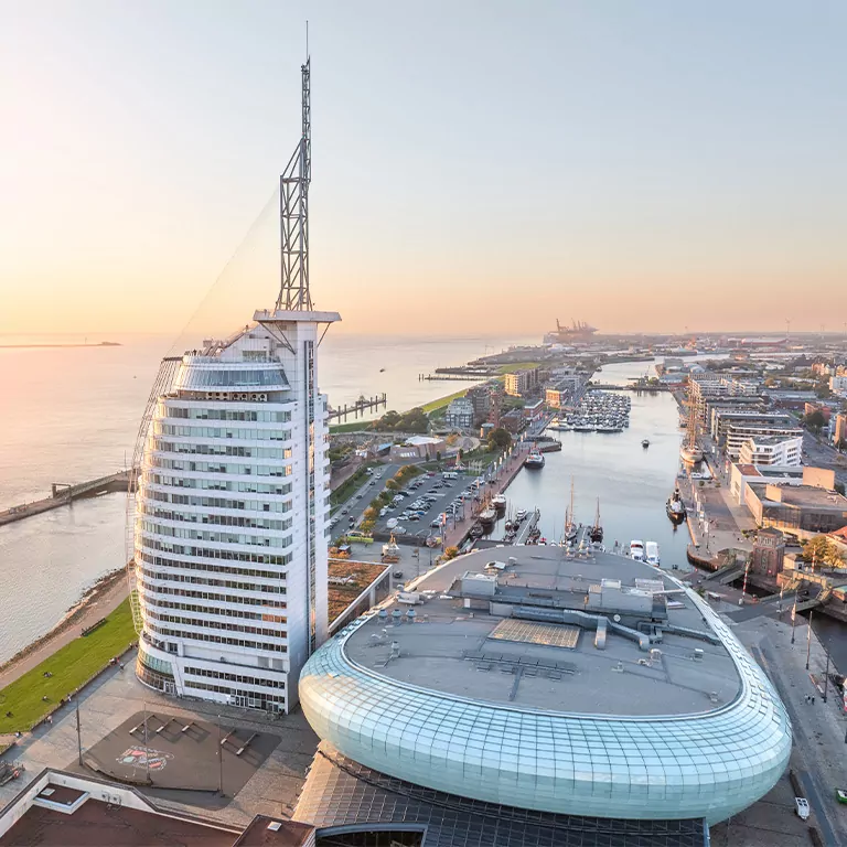 ATLANTIC Hotel Sail City, Klimahaus, Auswanderer Museum am Wasser bei Sonnenuntergang, mit Blick auf Hafen und Stadtlandschaft.