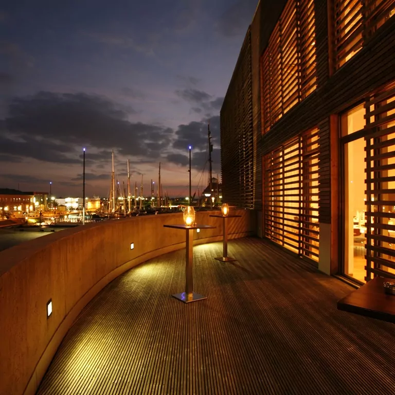 Terrasse vom Tagungsraum New York Saal im deutschen Auswandererhaus bei Abenddämmerung mit Hafenblick, stimmungsvolle Beleuchtung und Holzverkleidung.